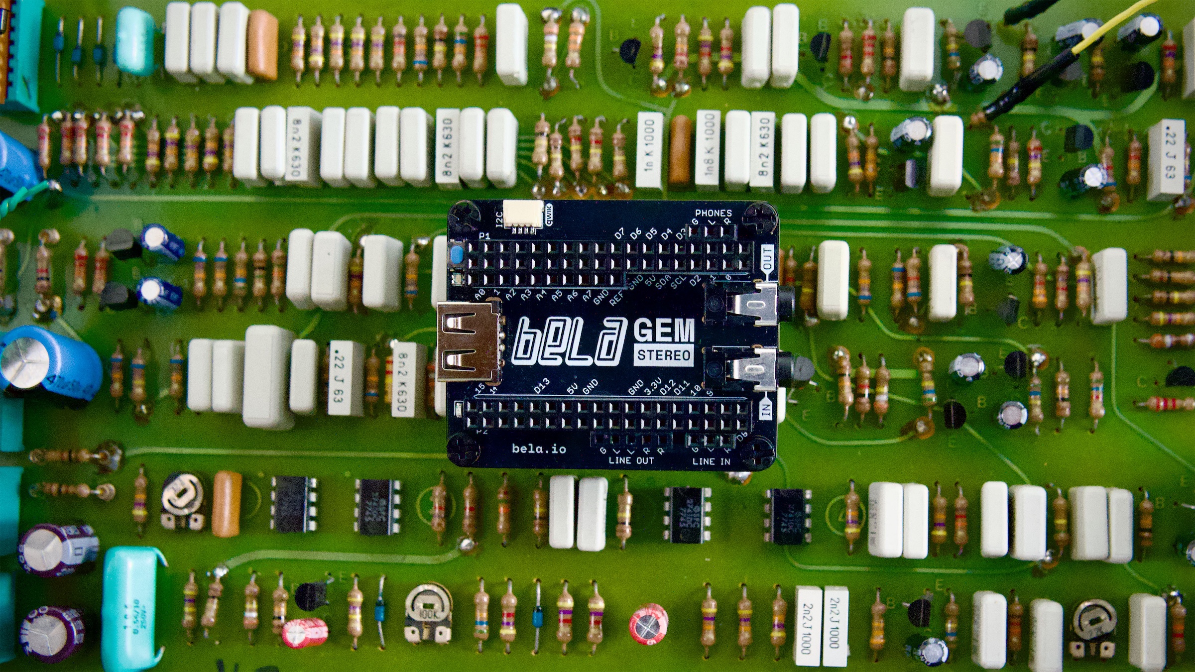 A Bela Gem system at an angle, surrounded by various electronic parts and components