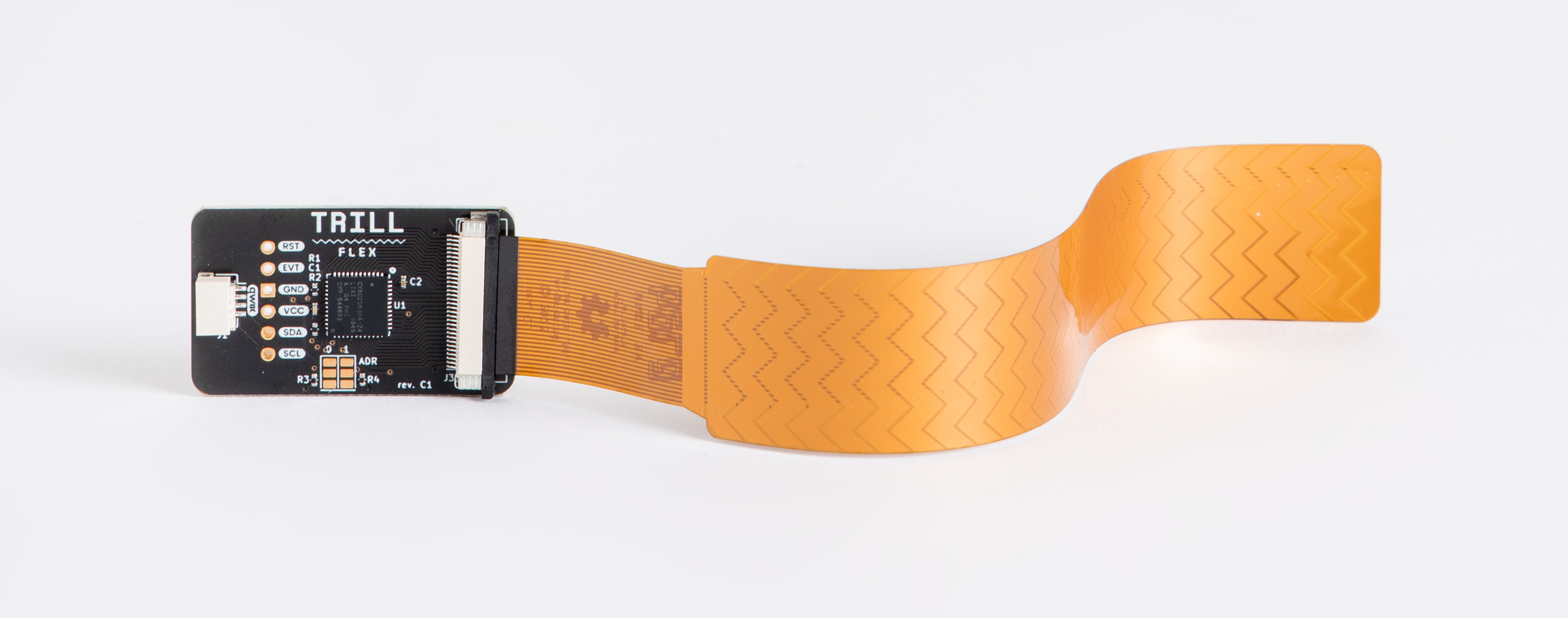 A Trill Bar sensor held in a hand against a soft-focus studio background